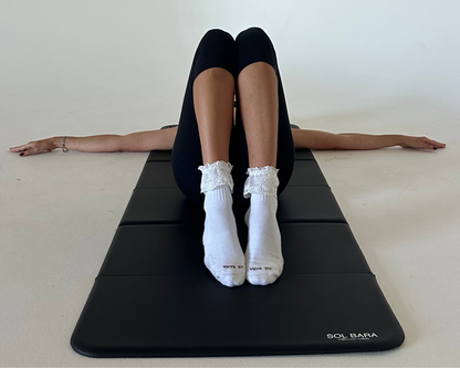 The Lacey bamboo grip socks in white with ivory lace trim, worn on a Pilates mat